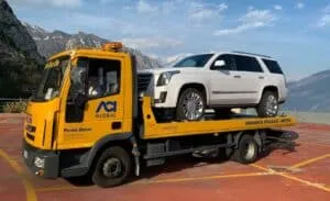 Carro attrezzi giallo che trasporta un SUV bianco sul pianale