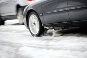 Auto in movimento su strada innevata con la neve sollevata dalle ruote