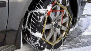 Ruota di un'auto con le catene da neve montate su strada innevata