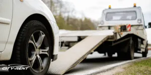 Auto bianca caricata sul pianale di un carro attrezzi a bordo strada